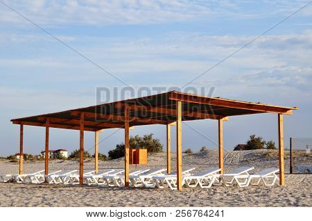 Wooden Canopy With Sun Loungers On The Beach At Dawn.