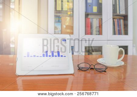Mock Up Image Of White Tablet Pc With Black Blank Screen And Coffee Cup On Wooden Table In Blur Offi