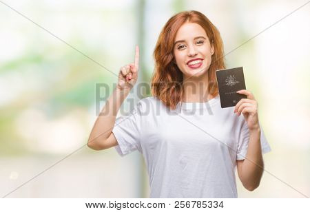 Young beautiful woman holding passport of australia over isolated background surprised with an idea or question pointing finger with happy face, number one