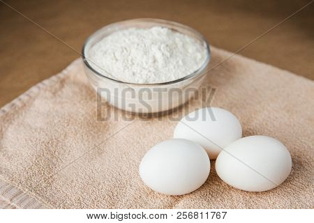 White Chicken Eggs And Bowl With Flour On Brown Towel