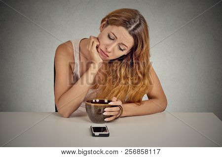 Sad Depressed Young Woman Sitting At Table Drinking Coffee Looking At Her Mobile Phone Waiting For A