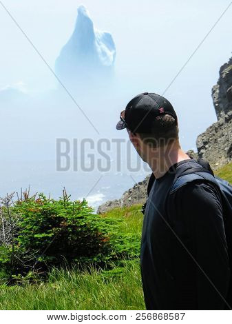 Trinity, Newfoundland - July 17th, 2014: A Young Tourist Viewing An Incredible Iceberg Floating Alon