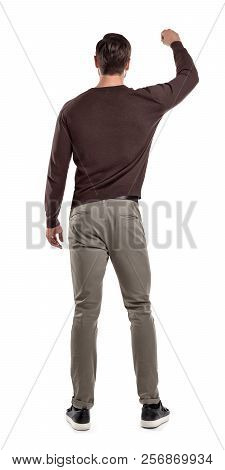 A Fit Man In Casual Sweater Stands In A Back View With One Arm Lifted Up As If Holding Something In 