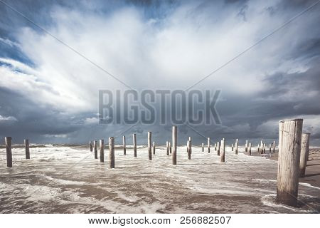 Long Shutter Photo Of Wooden On Sandy Beach With White Clouds And Waves Of The North Sea