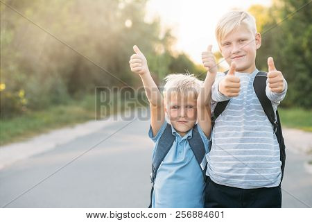Two Heerful Blondy Boys Gives A Thumbs-up. Schoolboys Smiling And Happy.