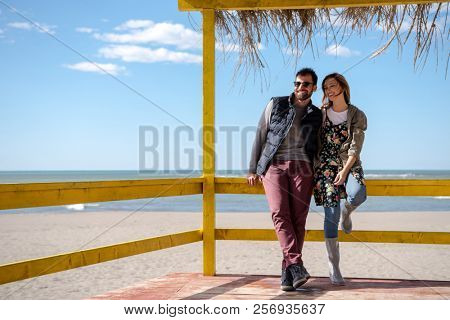 Happy couple enyojing time together on beach during autumn day