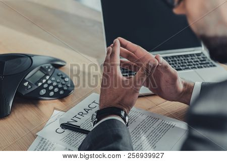Cropped Shot Of Businessman With Laptop And Contract Using Speakerphone At Office