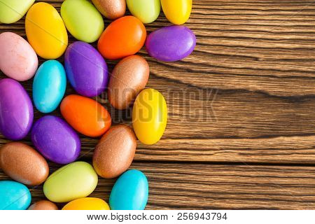 Brightly Colored Sugar Coated Fresh Roasted Almonds On Wood With Copy Space Viewed From Above