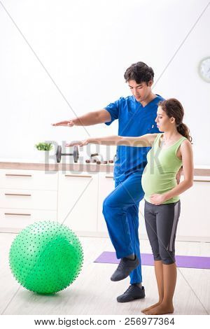 Pregnant woman doing physical exercies with instructor