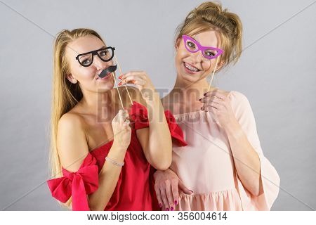 Happy Two Women Holding Paper Decoration Photo Booth Mask Glasses And Moustache On Stick, Having Fun