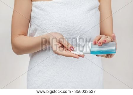 Close-up Woman In Towel Holding Cotton Pad And Makeup Remover In Her Hands. Woman Applying Lotion To