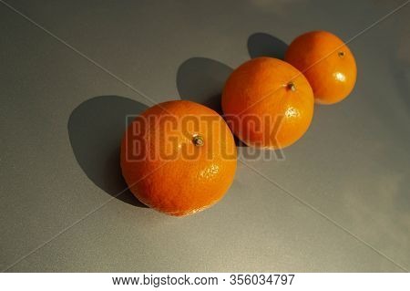 Three Tangerines In Line On A Gray Background