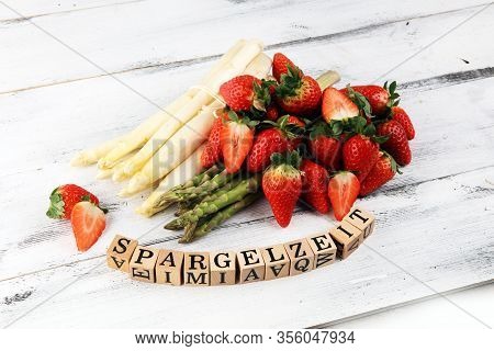 White And Green Fresh Asparagus With A Bunch Of Healthy Strawberries With Spargelzeit Wooden Letter.