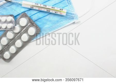 White Medicine Blister Packs Pills, Thermometer, Medical Face Mask Close-up Flat Lay Isolated On Whi