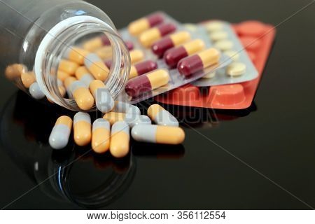 Medications In Tablets And Capsules On Dark Glass Table. Variation Of Drugs, Protection And Profilac