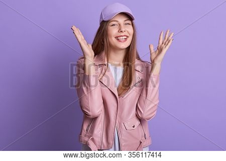 Indoor Portrait Of Young Teenager Raising Hands, Having Good News, Smiling Sincerely, Looking Direct