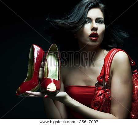modello di moda con borsa rossa e scarpe rosse. su sfondo nero.