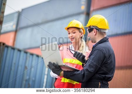 Female Dock Worker Wearing A White Helmet Yellow Standing In A Industrial Shipping Yard She Discussi