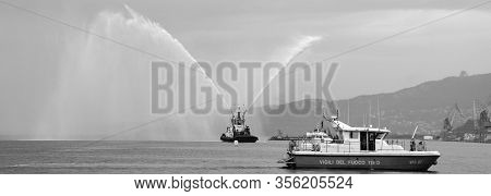 Trieste Italy 05 19 2019: Deneb Tug Boat In Trieste Italy Giving Farewell Salute With Fire Hoses Wit