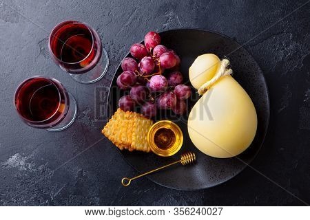 Caciocavallo Cheese With Grapes, Crackers And Red Wine. Dark Background. Top View.