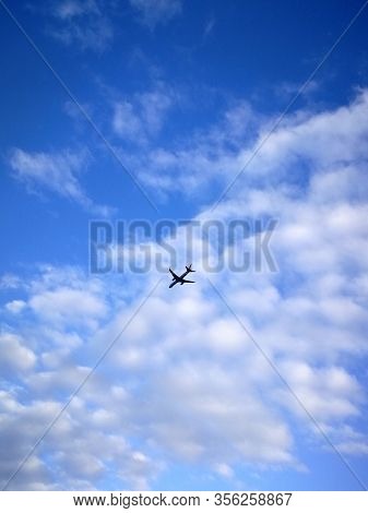 Airplane in the sky with small white clouds