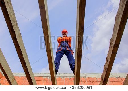 Construction Worker On Construction Site. Roofer Carpenter Builder Working On Roof Structure On Cons