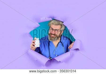 Pharmaceutical Drug. Bearded Doctor. Doctor With Stethoscope Holds Pills. Through Paper. Doctor With