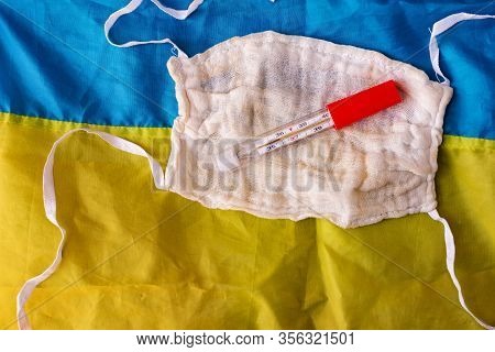 Reusable Gauze Protective Masks And Thermometer On A Blue-yellow Background. View From Above. The Sp