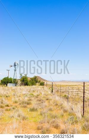 Windmill On A Farm In Rural Grassland Area Of South Africa