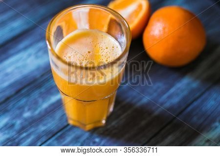 Glass Of Orange Juice On A Blue Table With Oranges