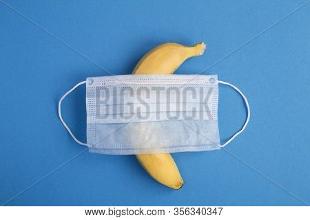 Creative Composition Witn Medical Mask And Banana In The Center Of The Blue  Background. Top View. C