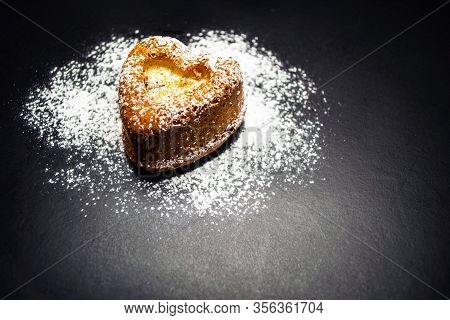 Heart Shaped Sponge Cake Sprinkled With Powdered Sugar. Black Background.