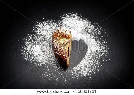 Heart Shaped Sponge Cake Sprinkled With Powdered Sugar. Black Background.