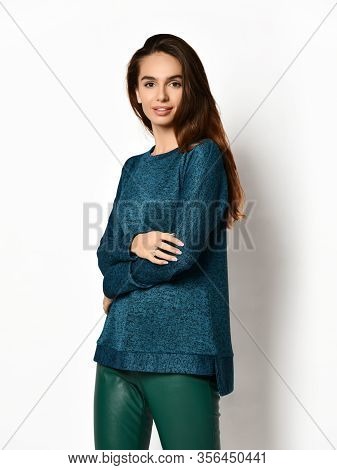 Smiling Young Pretty Brunette Woman In Casual Blue Sweatshirt Jersey And Grey Leather Jeggings Is Po