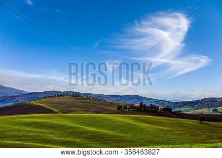 Agritourism. Rural farms and  picturesque hills of Tuscany after harvest. Light clouds over Tuscany hills. Beautiful Italy. The concept of active, rural and photo tourism