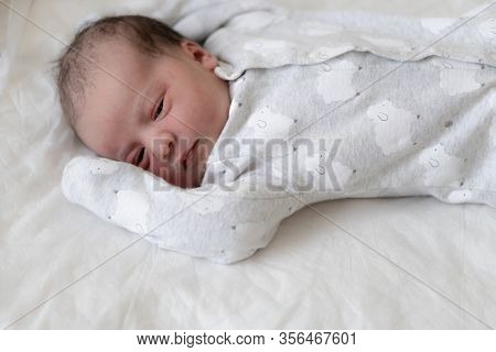 A Newborn Baby Lies On Its Back With Open Eyes In The First Minutes Of Life. A Newborn With Traces O