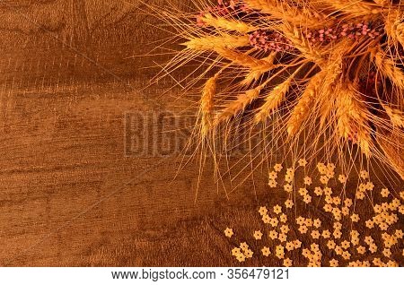 Golden Ears Of Ripe Wheat On A Jute Bag And Small Pasta On A Dark Table