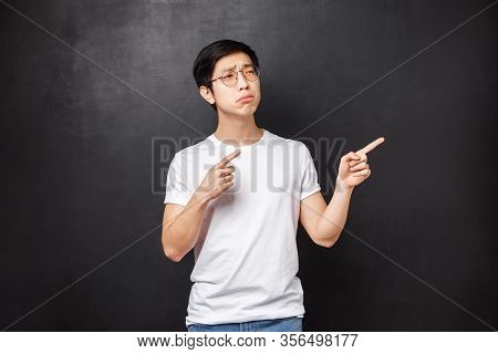 Portrait Of Skeptical And Displeased Young Picky Asian Guy Looking Doubtful At Product, Being Unsure