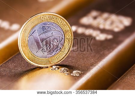 One Real Coin And Gold Bars. Concept Of Appreciation Of The Brazilian Currency In The Stock Market.