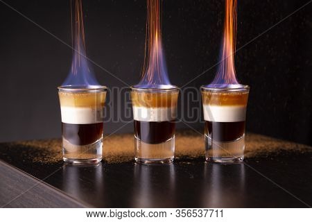 Three Shots Of Flaming B-52 Cocktail Placed On A Bar Counter