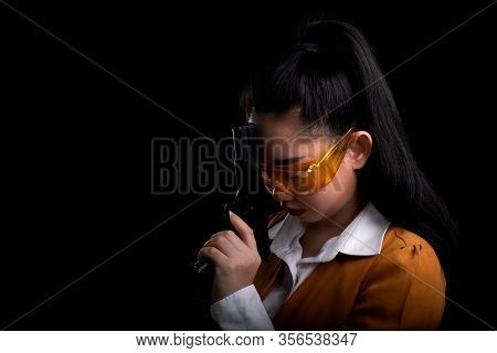 Portrait Beautiful Asea Woman Wearing A Yellow Suit One Hand Holding Pistol Gun At The Black Backgro