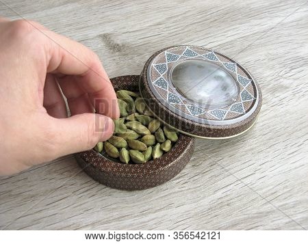 Dish Of Green Cardamom Pods With Male Hand On Table. Ingredients For Healthy Cooking. Ayurvedic Trea