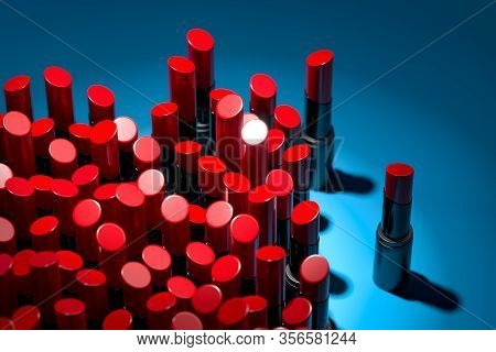 Red Glossy Lipsticks On Blue Background Illuminated By Spotlight. Cosmetics For Modern Luxury Make U