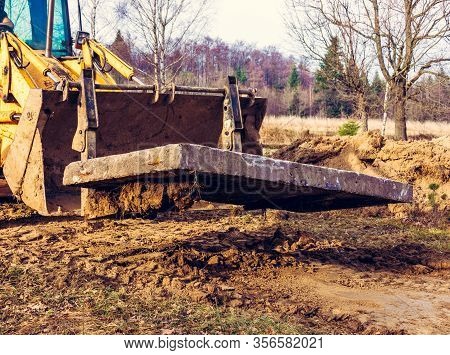 The Yellow Excavator Transports Concrete Slabs In The Countryside.