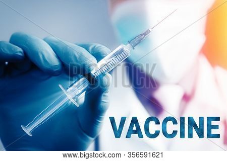 Close Up Hand Of Doctor In Blue Latex Glove And Medical Gauze Mask With Transparent Syringe. Health 