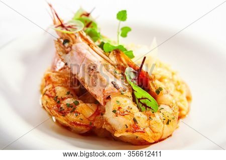 Risotto tom yam with argentinian shrimp. Delicious thai dish with seafood closeup view. Traditional asian meal with rice and aromatic greenery. Food composition on white plate. Restaurant delicacy