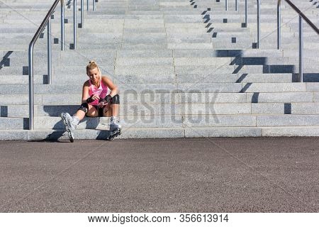 Young attractive woman adjusting safety gear while wearing rollerblades
