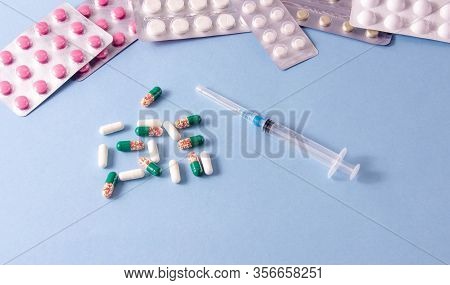 Coronavirus Phrase Text On A Blue Background With Medicines And A Syringe. The Concept Of The New 20