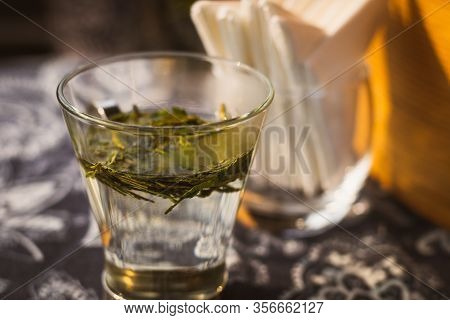 Longjing Dragon Well Tea Leaves On A Small Glass With Warm Water