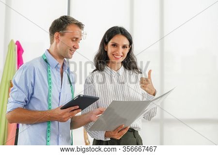 Fashion Designer Room, Man And Woman Working In Home Base Cloth Design Business. Young Client Is Com